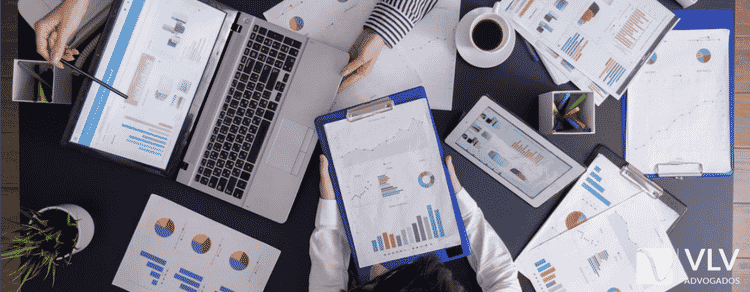 Publicidade digital e direito do consumidor: cuidados que empresas precisam ter ao vender online 1 Equipe analisando dados e estratégias de publicidade digital em computadores e documentos sobre marketing e vendas online